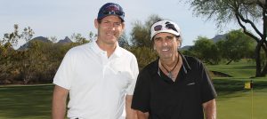 Steve Young posing next to a player in the Desert Classic Golf Tournament on the golf course.