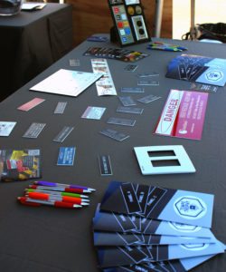Brochures, pens, and sample products on top of the table at the Tempe Trophy booth.